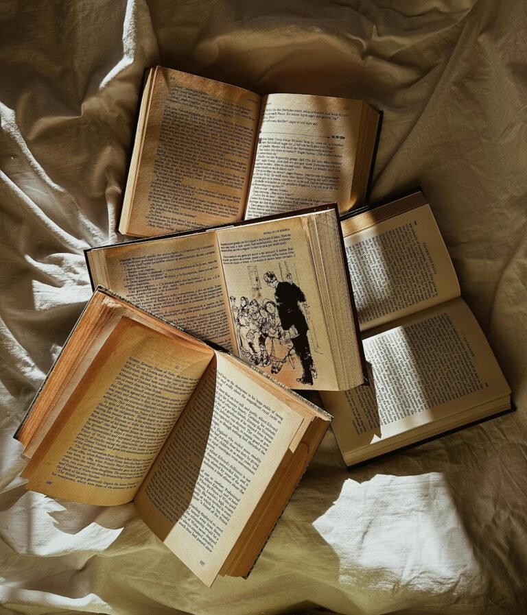 free photo of pile of open books lying on bed sheets